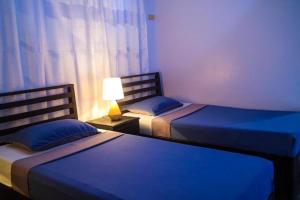 公主港Hostel Privado的一间卧室设有两张床和一张桌子上的台灯。