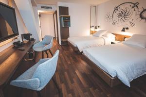 日内瓦日内瓦伯尔尼纳酒店的酒店客房带两张床、一张桌子和椅子。