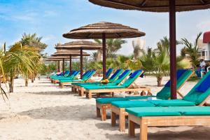 沙迦Sahara Beach Resort & Spa的海滩上一排沙滩椅和遮阳伞