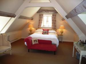 伯福德The Swan Inn Swinbrook的一间卧室配有一张床和一张红色椅子
