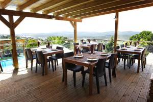 圣布拉什迪阿尔波特尔Hotel Rural Rocha da Gralheira的一间在甲板上配有木桌和椅子的餐厅