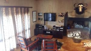 KleinvieGannabos Guest House的客厅配有电视和桌椅
