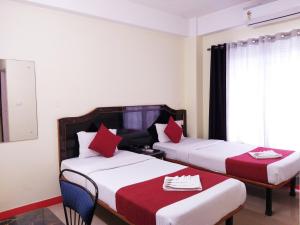 西里古里HOTEL NILADRII GALAXY的酒店客房 - 带两张带红色枕头的床