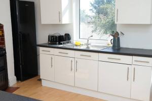 赫尔Hullidays - University Side Lg 4 bed House的厨房配有白色橱柜、水槽和窗户。
