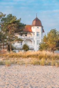 宾茨Strandhotel zur Promenade的海滩上一座白色的大建筑,有红色屋顶