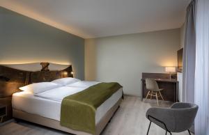 罗森海姆罗森海姆温德姆特里普酒店的一间卧室配有一张床、一张桌子和一把椅子