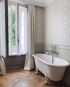 Belleville-en-Beaujolais花园旅馆的带窗户的浴室内的白色浴缸