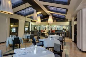 罗马罗马皇宫大酒店的餐厅设有白色的桌椅和吊灯。