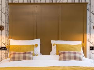 塔维斯托克The Cornish Arms的一张带黄色床头板的床和两个枕头