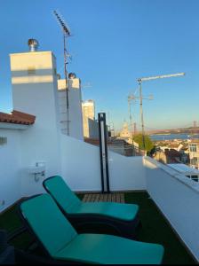 里斯本quarto suite em Belém的大楼内的阳台配有两把绿色椅子