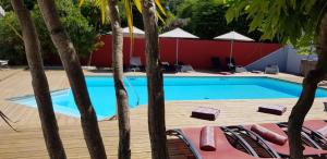 诺亚芒提亚La Villa en L'île - 2 Piscines & Spa的游泳池旁设有椅子和树木