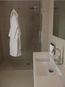 Castle Hedingham潘纳阿斯套房住宿加早餐旅馆的浴室设有水槽和带白色毛巾的淋浴。
