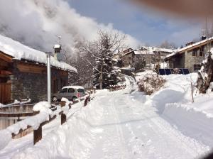 Rhemes-Saint-Georges嘉德梅森酒店的一条雪覆盖的街道,汽车驶向这条街道