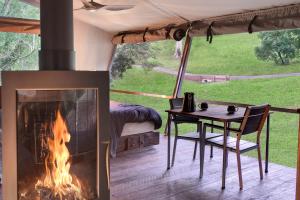 WoombyeStarry Nights Luxury Camping的帐篷内的壁炉,配有桌子和床