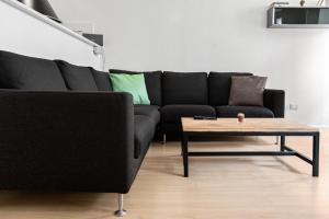 特伦托Duomo Flat的客厅配有黑色沙发和咖啡桌