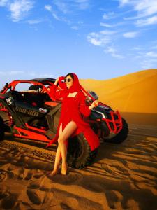 敦煌敦煌薇薇安VIVIAN国际沙漠露营基地的坐在沙漠中阿伏的红色衣服上的女人