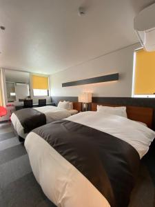 大阪Hotel 草石庵的白色和黑色的酒店客房内的两张床