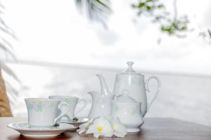尼甘布Araliya Lagoon Park Resort的桌子上一团白花瓶和杯子