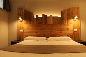 奥斯塔蒙特艾米流斯酒店的一间卧室配有一张大床和木制床头板