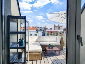 维也纳Boutique Design-Apartments Vienna的阳台的沙发上配有遮阳伞