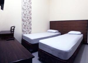 三宝垄Hotel Pelangi Indah的一间卧室配有两张床、一张桌子和一把椅子