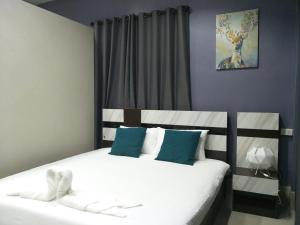 勿洞Betong Cozy Guesthouse เบตง โคซี่ เกสต์เฮาส์的一间卧室配有两张带白色和蓝色枕头的床