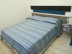 诺利6 stelle e relax...nientaltro的卧室内的一张带蓝色和白色条纹棉被的床