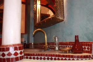 马拉喀什里亚德洛斯亚摩洛哥传统庭院住宅的浴室水槽设有铜水龙头和镜子