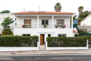 埃里塞拉Beachouse - Surf, Bed & Breakfast的带阳台的白色房屋,配有椅子
