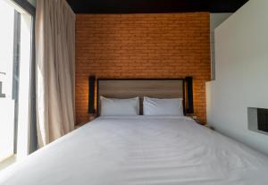 达喀尔达喀尔奥诺莫酒店的卧室配有一张白色大床和砖墙