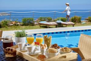 巴利恩Okeanides Villas的一张桌子,旁边是游泳池,提供早餐食品和饮料