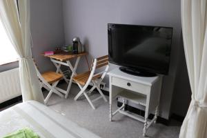 ZandbergenB&B Den Boskant的客厅配有电视和桌椅