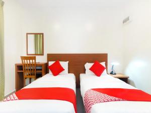 马六甲Lawten Hotel的宿舍间内的两张床,配有红色枕头