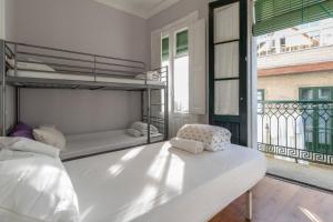 雷东德拉Albergue Casa de Abreu的一间白色卧室,配有双层床和阳台