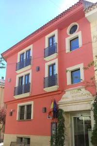 比利亚罗夫莱多理想酒店的一座红色的建筑,旁边设有阳台