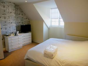 Highworth萨罗森海德宾馆的卧室配有白色的床和电视。