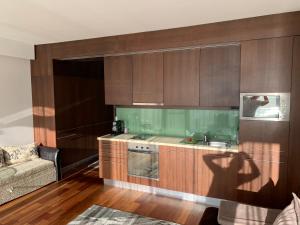 巴拉通雷勒Bavaria Club Apartman的厨房配有木制橱柜、水槽和沙发。