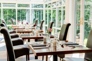 贝图瑟科伊德克雷格德文滨江酒店的餐厅设有木桌、椅子和窗户。