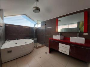 伊洛Apart Hotel Atenea的带浴缸、两个盥洗盆和镜子的浴室