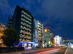 大阪Hotel Pivot Shin-Imamiya Ekimae的一条城市街道,晚上有高大的建筑