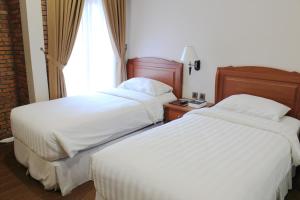 棉兰Thong's Inn Hotel Kualanamu的酒店客房设有两张床和窗户。