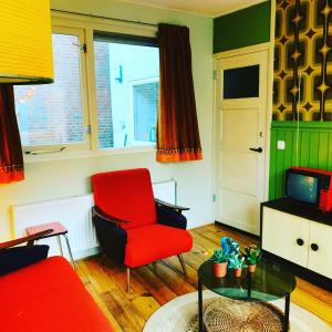 OlstRetro-huisje GoedFout的客厅配有红色椅子和电视