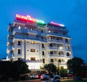 绥和市金玉庆酒店的一座白色的大建筑,上面有 ⁇ 虹灯标志
