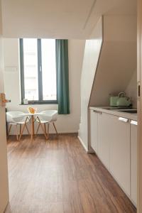 新乌尔姆Soulfactory Apartments的厨房配有白色橱柜和桌椅