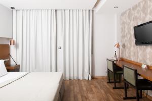 雅典雅典之A酒店的酒店客房配有一张床、一张书桌和一台电视。