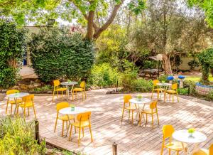 Gesher HaZiw盖舍尔哈兹威旅游酒店的庭院配有白色的桌子和黄色的椅子