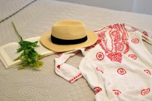 Mandrakia爱琴海蓝色度假屋的床上的帽子和毯子及一本书