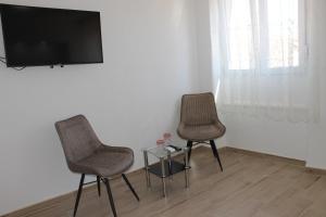 扎达尔Jeta Studio & Rooms的两把椅子和一张桌子,墙上配有电视