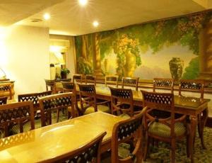 曼谷Diamond City Hotel SHA Certified的餐厅设有桌椅,墙上挂着一幅大画