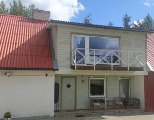 ValgmaSaadjärve Kingu talu puhkemaja的一座红色屋顶的房子和一个阳台